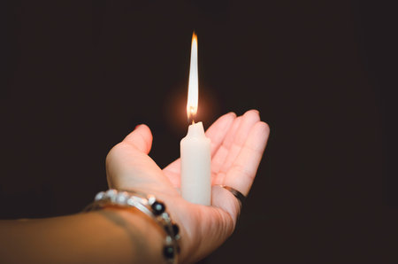 hand holding a burning candle in dark.の写真素材