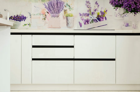 White stylish kitchen furniture without handles, close-up. The concept of a modern interior.