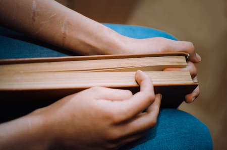 Scarred hands hold a book.の写真素材
