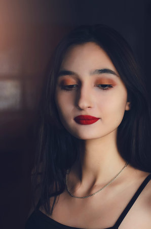 Portrait of a beautiful dark-haired girl with red lipstick on her lips. Vertical photography.