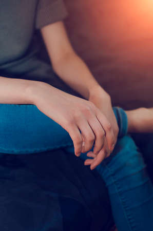 The girl sits on the couch in the room with her hands folded on her knees.の写真素材