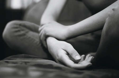 girl sitting with her arms crossed, close-up. Black and white photography.の写真素材