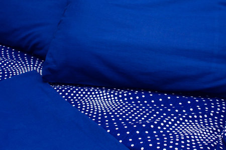 blue pillows, duvet and duvet case on a bed. blue bed linen on a blue sofa. Close-up cozy home background.の写真素材