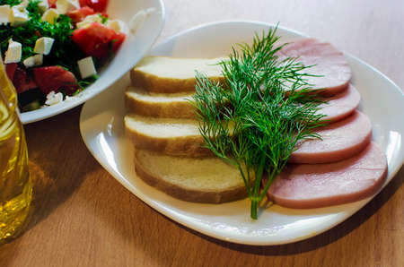 dish with sliced ham, dill greens and loaf.の写真素材