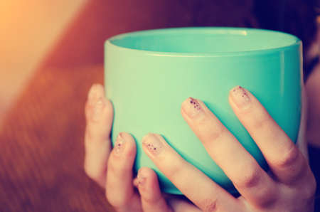 A girl holds a large cup of tea in her hands, close-up. Autumn, cold concept.の写真素材