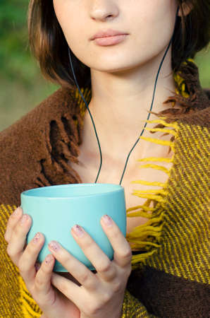 Girl holding a cup of hot tea in her hands, close-up.の写真素材