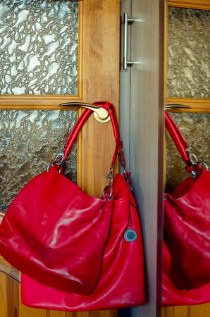 A red bag hangs on the door handle. Everyday home environment.の写真素材
