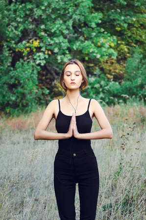 The girl is engaged in physical exercises in the park. Yoga classes outdoors.の写真素材