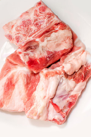 Pork ribs for making soup on a white plate, close-up.