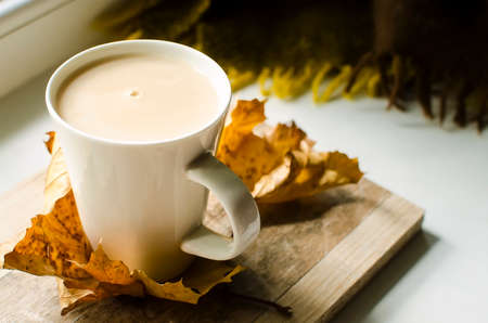 autumn cozy still life with a cup of coffee with milk and yellow autumn leaves. Autumn background for articles and blog.の写真素材
