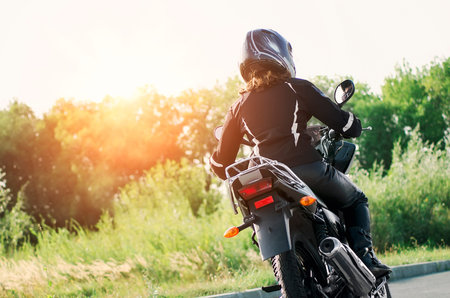Biker girl in a leather jacket and helmet on a motorcycle