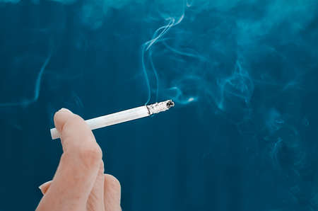 smoking cigarette in hand. Close-up, selective focus.の写真素材
