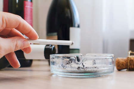 A smoking cigarette in a woman's hand close-up. Concept of unhealthy lifestyle.の写真素材