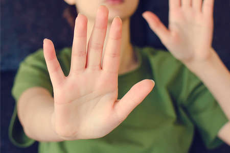 Blurred portrait of young lady extending hand forward saying no enough. Focus on female palm close up raised in prohibiting gesture. shows stop sign prohibition symbol keeps palm forward to camera.の写真素材
