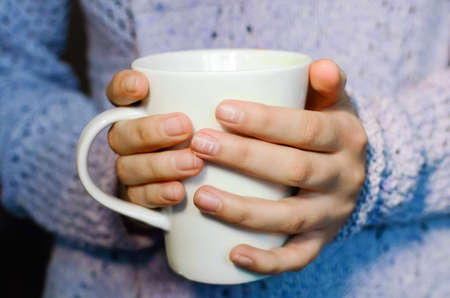 White Cup of tea in the hands of a girl, close-up. lifestyle concept.の写真素材