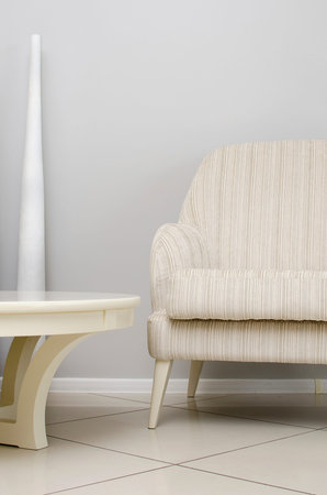 Minimalistic living room interior with soft armchair and white coffee table, vertical photo.
