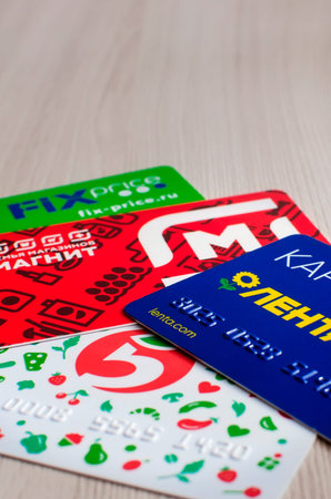 Saratov, RUSSIA - March 27, 2022: A Helping Cards of various stores on wooden table, russia