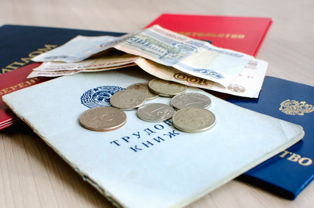 A certificate, a diploma and a work book are lie next to Russian money. Unemployment concept.のeditorial素材