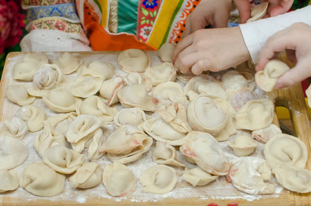 The children's hands, soiled with flour, neatly laid out handmade, freshly ravioli, meat dumpling or dumplings on cutting boards. Teaching children to cook homemade food, joint work. selective focus.の写真素材