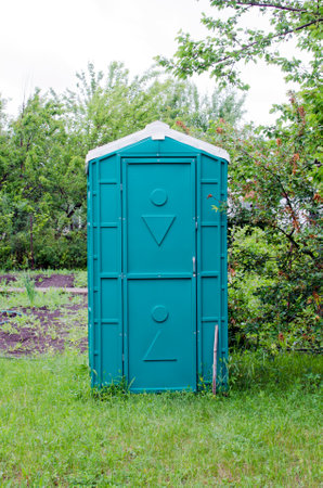 Green portable plastic toilet .Transportable modern designed street toilet is placed atcountry cottage area, outdoor privacy.の写真素材