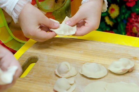 Children's hands make dumplings. Master class on making dumplings. Close-up, selective focus.の写真素材