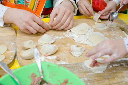 Children's hands make dumplings. Master class on making dumplings. Close-up, selective focus.の写真素材