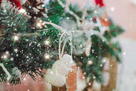 A New Year's toys hangs on a branch on a Christmas tree. Glowing festive background.の写真素材