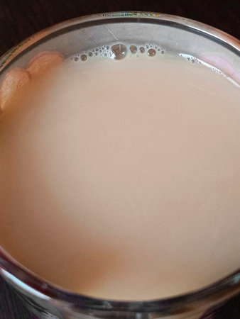 Liquid tea with milk is poured into a glass cup. Top view, macro.の写真素材