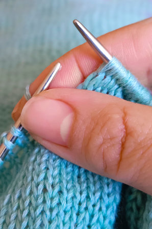 people and needlework concept - close up of woman hands knitting with needles and turquoise yarnの写真素材