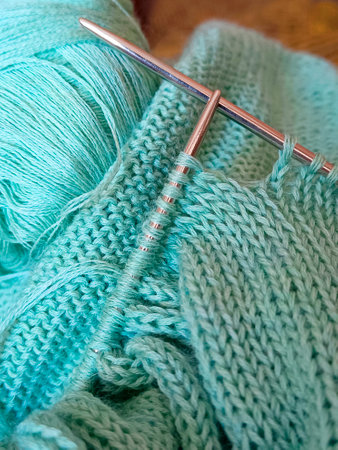 Female hobby knitting. Yarn in turquoise color And knitting needles. The beginning of the process of knitting a women's sweater.の写真素材