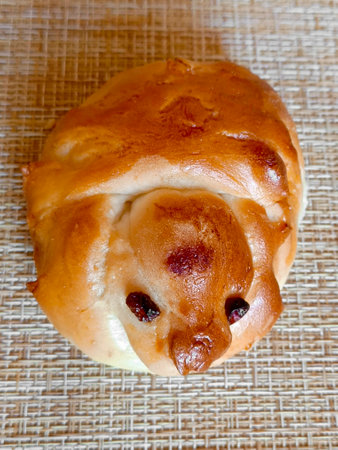 Single fresh baked raisin bun. Close-up, vertical photograph.の写真素材