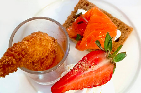 Serving food in a restaurant. Tiger shrimp, dessert with strawberries, toast with salted salmon.の写真素材