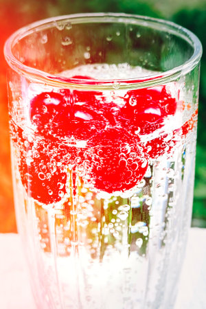 Red ripe cherries in a glass of mineral water. Concept of healthy natural nutrition, diet. Water bubbles on berries.の写真素材