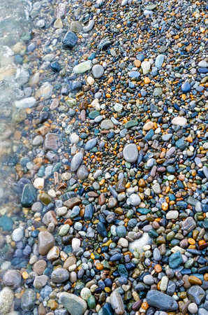 Abstract background with pebbles - round sea stones. Wet sea pebbles washed by sea waves. Vertical photo.の写真素材