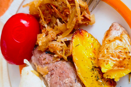 Close-up of cooked potatoes with meat and salted lying tomatoes on a plate.の写真素材