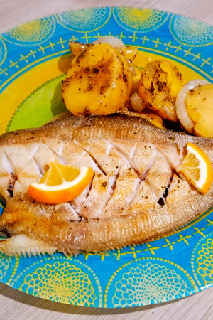 Baked flounder fish with onion, lemon and potatoes. Close-up, vertical photo.の写真素材