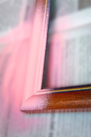 Wooden photo frame painted with pink spray paint. Close-up, selective focus. Vertical photo.の写真素材