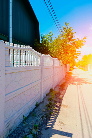 Decorative pink concrete fence on the background of green trees. Vertical photo.の写真素材