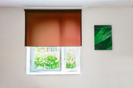 Brown roller blind on the window, close-up. Element of living room design.