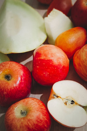 Ripe red apples and ripe melon lie in a heap on the table. Vertical photo.の写真素材