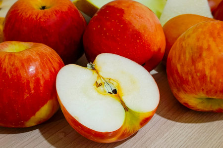 Ripe red apples and ripe melon lie in a heap on the table.