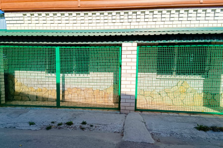 A modern fence made of green metal mesh and brick pillars.の写真素材