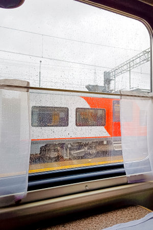 View from the train compartment window. Another train is visible in the window. Vertical photo. Concept of train travel in Russia.の写真素材