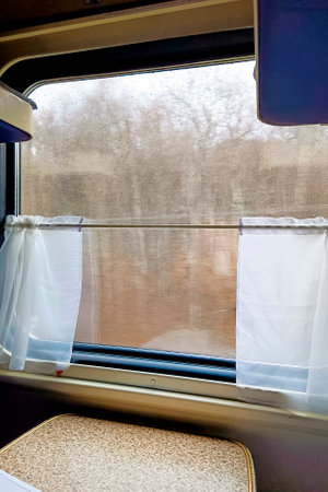 Vertical image of train interior and an autumn view on the window. Traveling with a train.の写真素材
