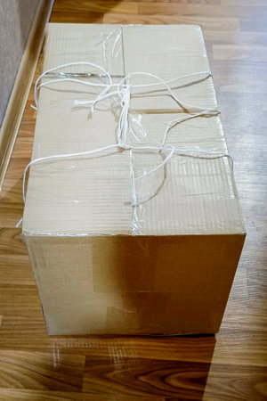 Packed cardboard box with things tied with rope. Moving concept. Vertical photo.の写真素材