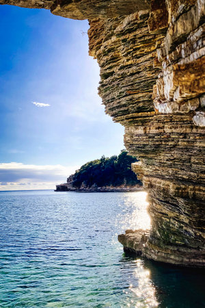 Rock cliff and geological stratum near the sea with cave at Italy.