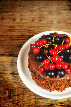 chocolate cake mini with red and black currants on a dark wood background. の写真素材