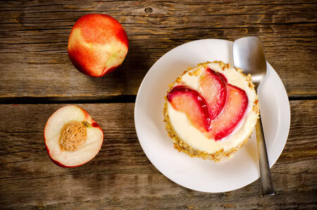 cheesecake mini with peaches on a dark wood background. toning. selective focus on slices of  peaches on the cheesecakeの写真素材