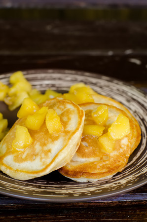 pancakes with caramelized apples on a dark wood background. toning. selective focus to the top of applesの写真素材