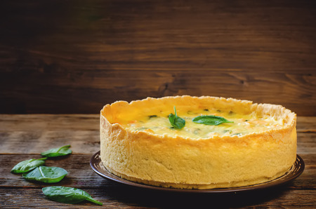 quiche with salmon and spinach on a dark wood background. toning. selective focus on the front of the pieの写真素材